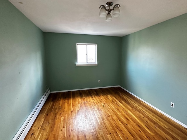 unfurnished room featuring wood-type flooring and a baseboard heating unit