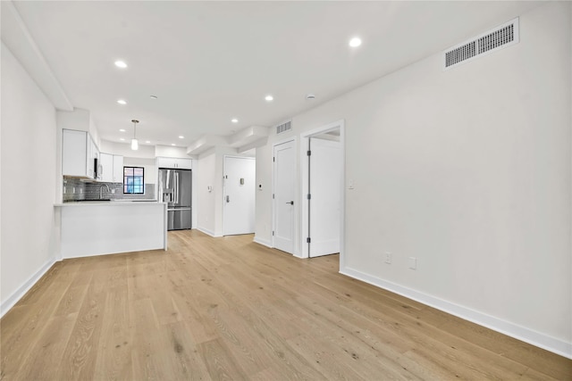 unfurnished living room featuring light wood-type flooring and sink