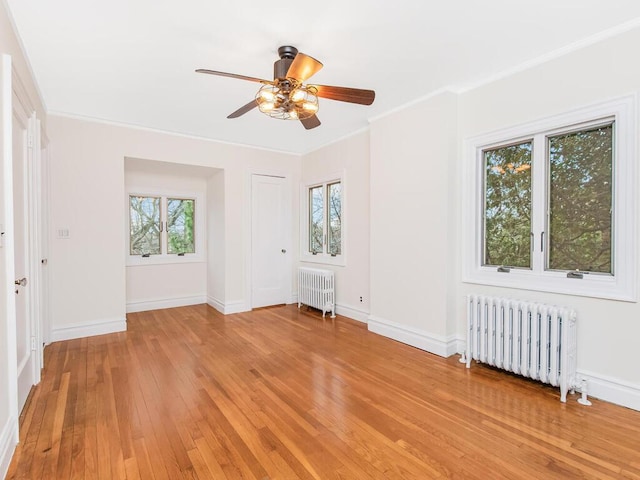 interior space with hardwood / wood-style flooring, ceiling fan, radiator heating unit, and ornamental molding