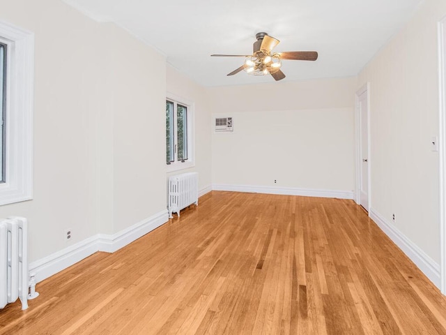 unfurnished room featuring light wood-type flooring, radiator, and ceiling fan