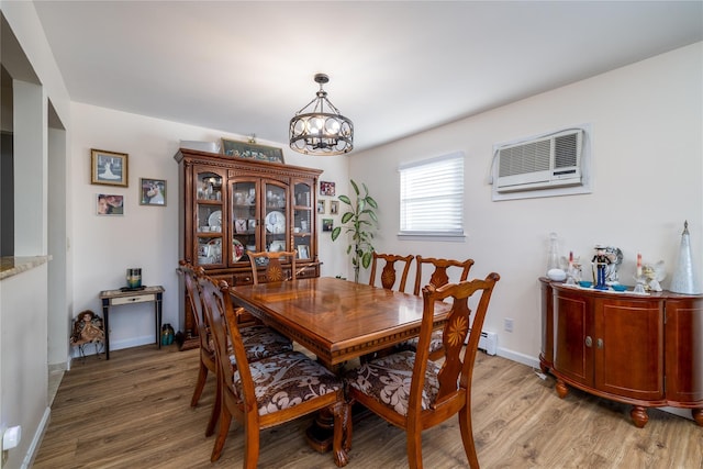 dining room with a chandelier, light wood-type flooring, and a wall mounted AC