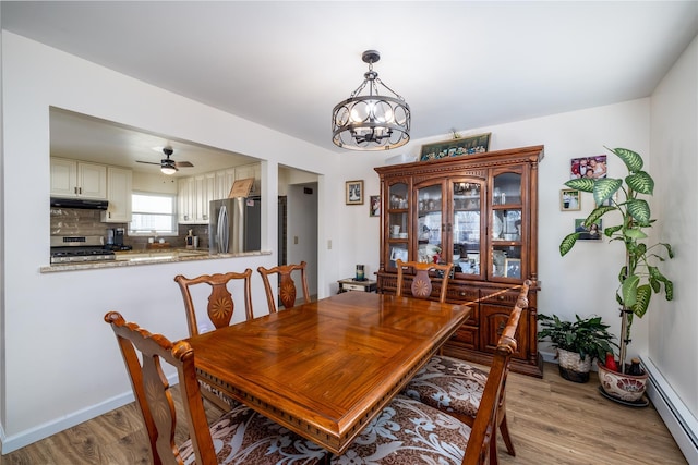 dining room with ceiling fan with notable chandelier, light hardwood / wood-style flooring, and baseboard heating