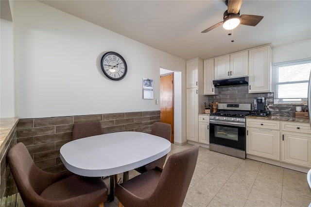 kitchen with backsplash, light stone countertops, stainless steel range, and ceiling fan