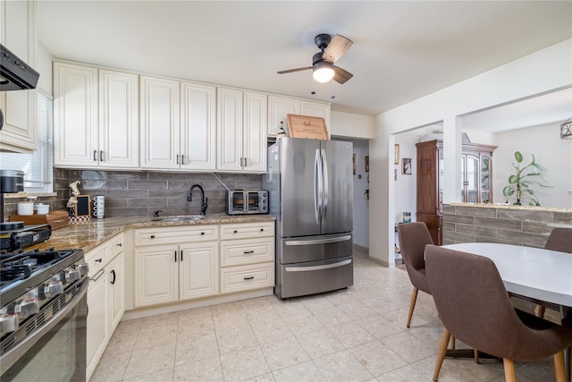 kitchen featuring sink, decorative backsplash, ceiling fan, light stone counters, and stainless steel appliances