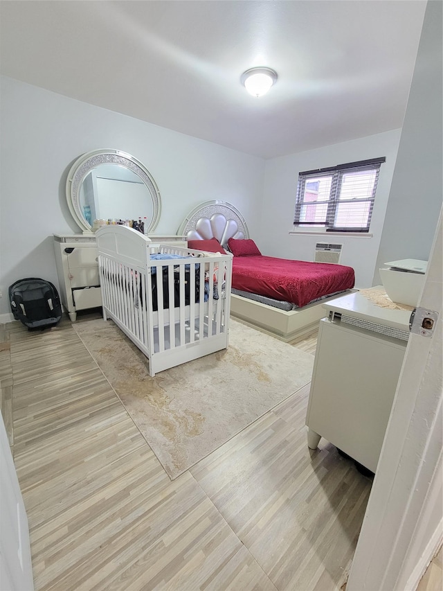 bedroom with a wall mounted air conditioner and light wood-type flooring