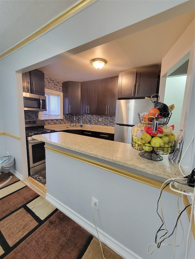 kitchen featuring decorative backsplash, appliances with stainless steel finishes, kitchen peninsula, dark brown cabinetry, and sink