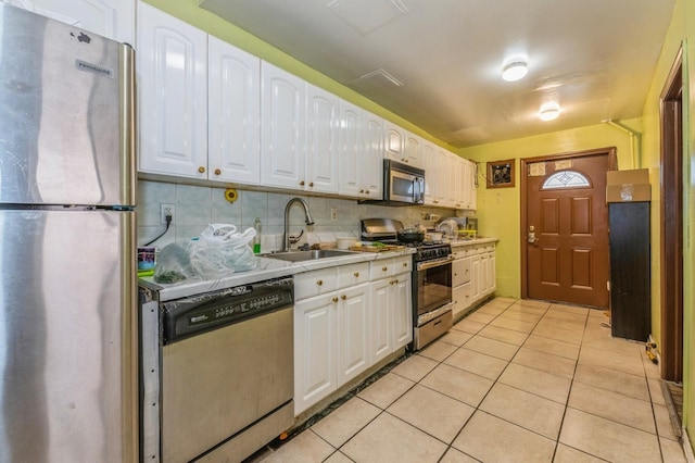 kitchen featuring appliances with stainless steel finishes, tasteful backsplash, sink, light tile patterned floors, and white cabinets