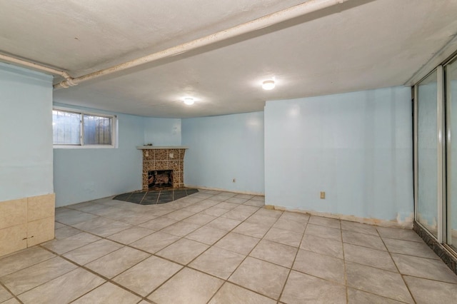 basement featuring light tile patterned flooring and a tiled fireplace