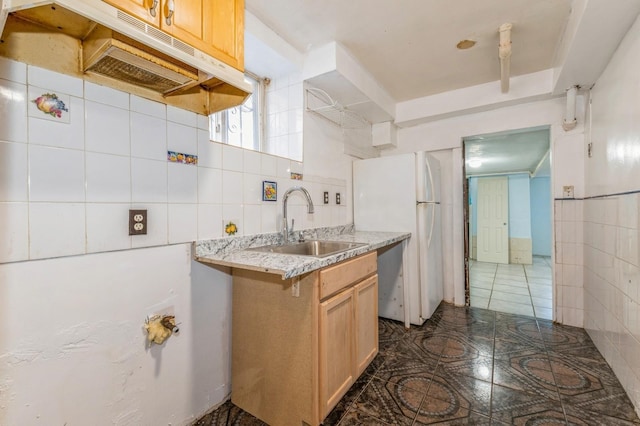 kitchen with tasteful backsplash, sink, tile walls, and light brown cabinets