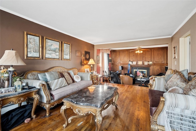 living room featuring hardwood / wood-style flooring, ceiling fan, and ornamental molding