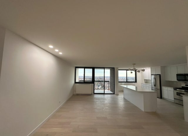 kitchen with stove, white cabinets, light wood-type flooring, a kitchen island, and stainless steel refrigerator