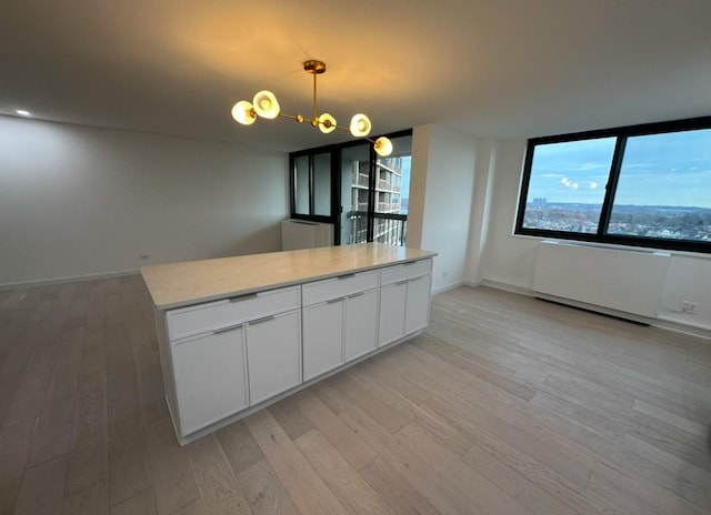 kitchen featuring white cabinets, pendant lighting, light hardwood / wood-style flooring, and a kitchen island