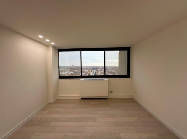 empty room with light hardwood / wood-style floors and radiator