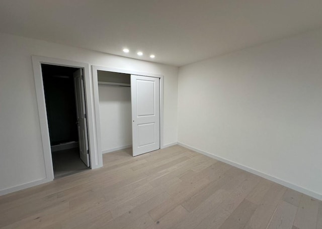 unfurnished bedroom featuring light wood-type flooring and a closet