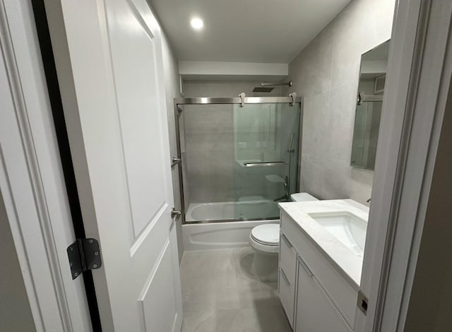 full bathroom featuring vanity, toilet, shower / bath combination with glass door, and tile walls