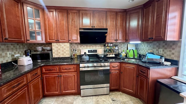 kitchen with decorative backsplash, stainless steel appliances, sink, dark stone countertops, and range hood