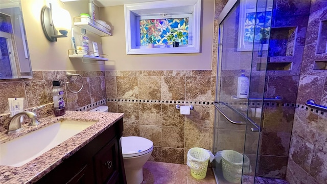 bathroom featuring vanity, toilet, a shower with shower door, and tile walls