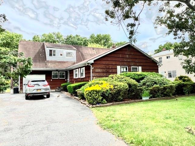 cape cod house with a front yard and a garage