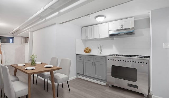 kitchen featuring gray cabinetry, white cabinetry, sink, light hardwood / wood-style flooring, and stove