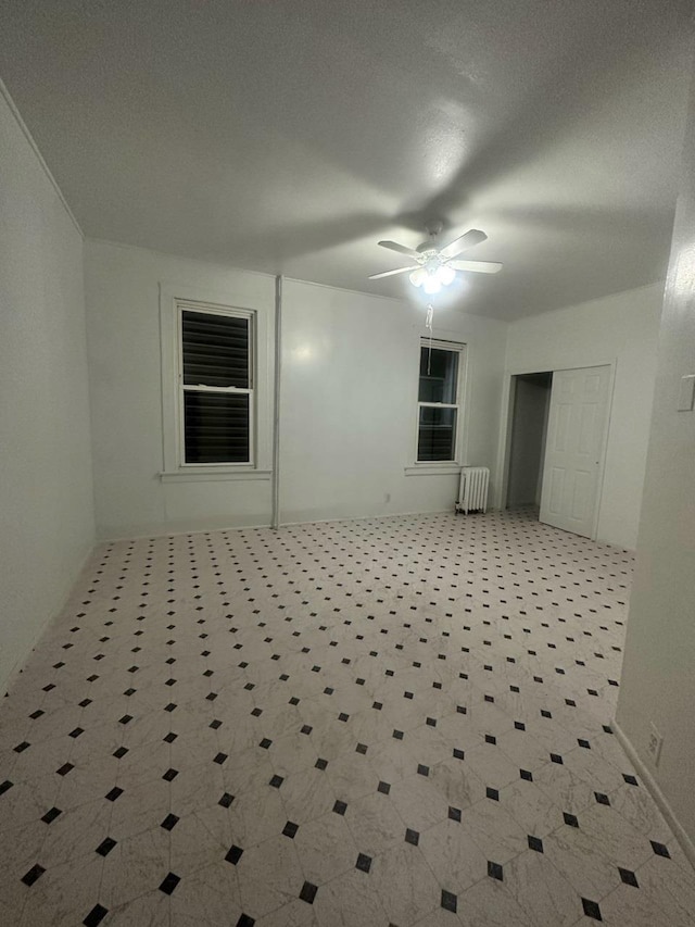 unfurnished room featuring radiator and ceiling fan