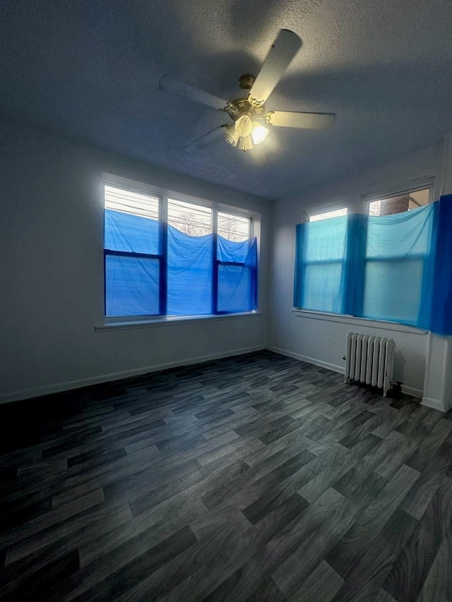 unfurnished room featuring ceiling fan, dark hardwood / wood-style flooring, a textured ceiling, and radiator