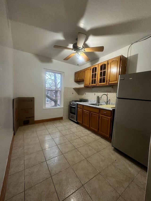 kitchen with appliances with stainless steel finishes, light tile patterned floors, ceiling fan, and sink