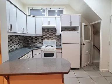 kitchen featuring kitchen peninsula, decorative backsplash, white appliances, light tile patterned floors, and white cabinets