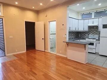 kitchen featuring decorative backsplash, white appliances, white cabinets, and kitchen peninsula