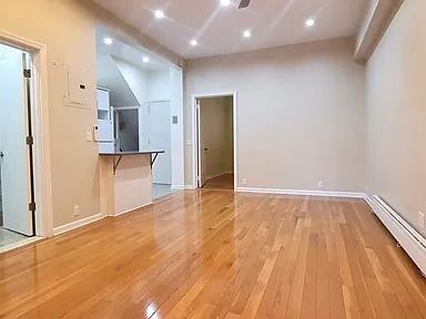 additional living space featuring a baseboard heating unit and hardwood / wood-style floors