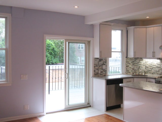 kitchen featuring decorative backsplash, stainless steel dishwasher, white cabinets, and sink