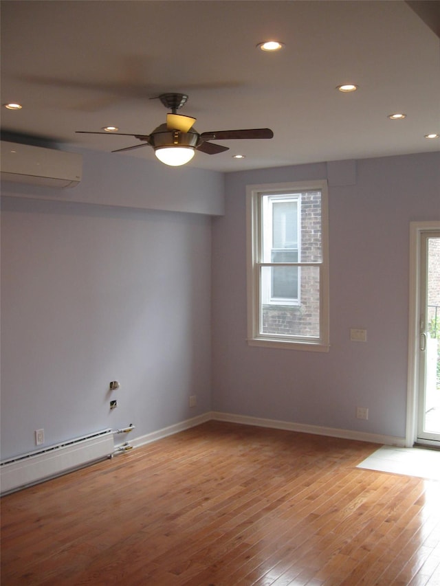 unfurnished room with ceiling fan, baseboard heating, light hardwood / wood-style flooring, and a wall mounted air conditioner