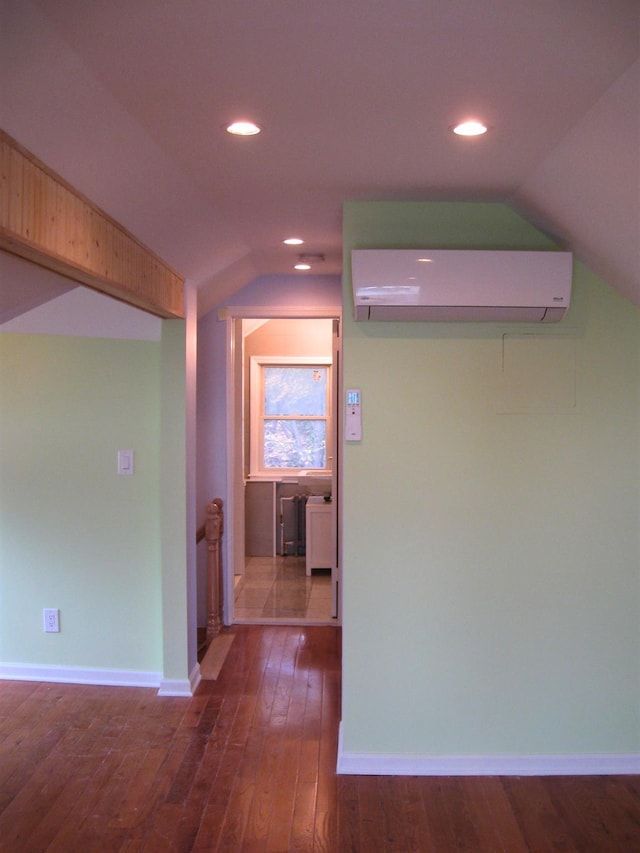 corridor with dark wood-type flooring, lofted ceiling, and a wall mounted AC