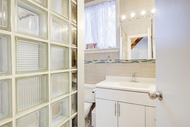 bathroom featuring tile walls, toilet, and vanity