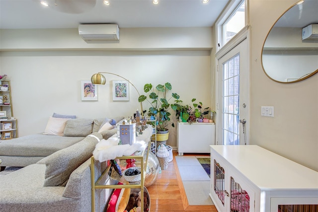 living room featuring a wall unit AC and light hardwood / wood-style floors