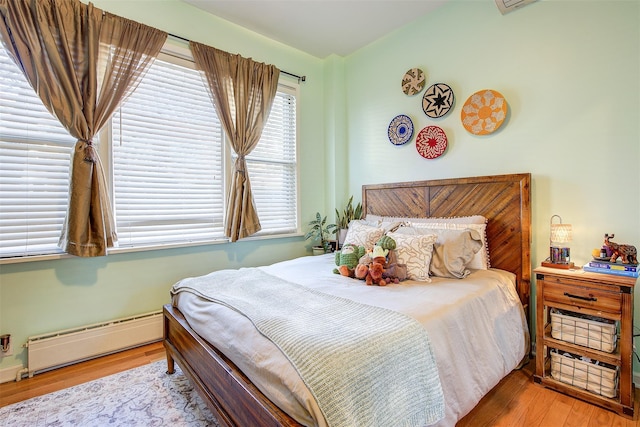 bedroom featuring a baseboard radiator, lofted ceiling, and light hardwood / wood-style flooring