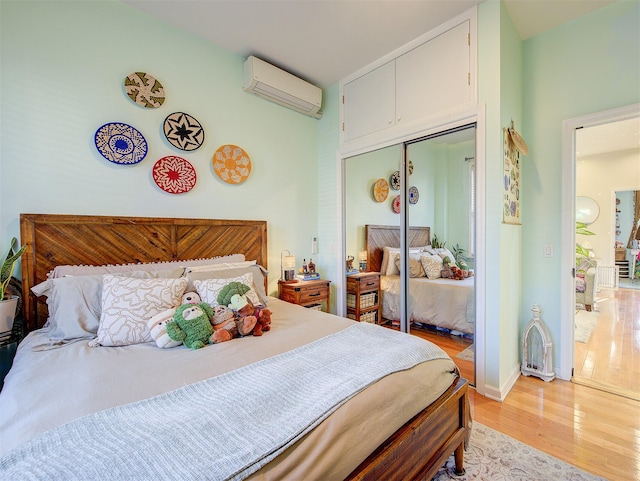 bedroom with a closet, a wall mounted air conditioner, and light hardwood / wood-style flooring