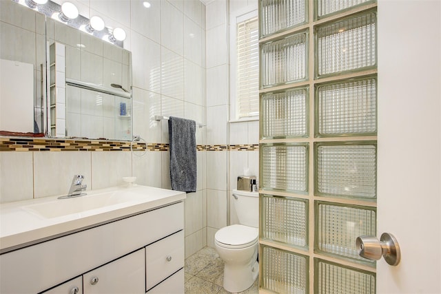 bathroom with vanity, toilet, and tile walls