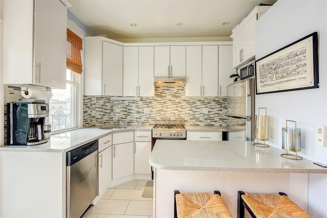 kitchen featuring sink, a breakfast bar, white cabinetry, backsplash, and stainless steel appliances