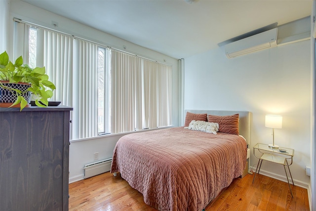 bedroom featuring light wood-type flooring, an AC wall unit, and baseboard heating