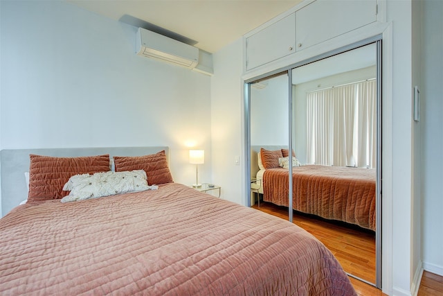 bedroom with a wall mounted air conditioner, light hardwood / wood-style floors, and a closet