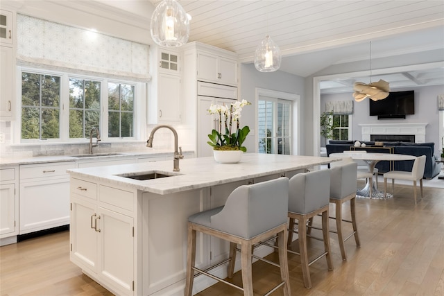 kitchen featuring a kitchen island with sink, decorative light fixtures, and white cabinetry