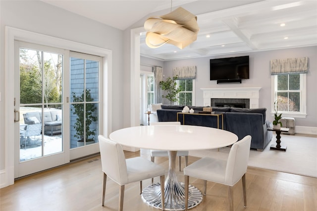 dining space with coffered ceiling, beam ceiling, and light hardwood / wood-style flooring