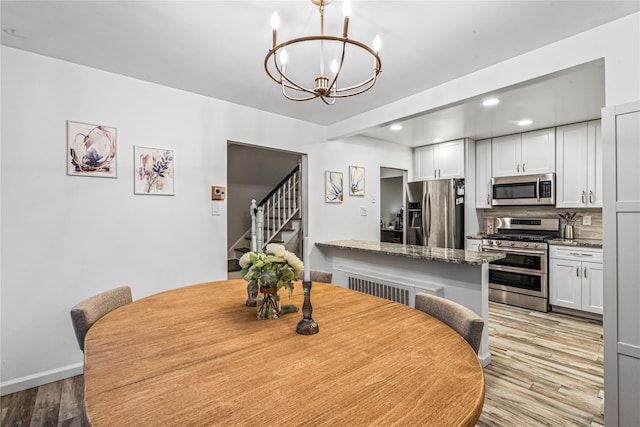 dining space with light hardwood / wood-style flooring and a chandelier