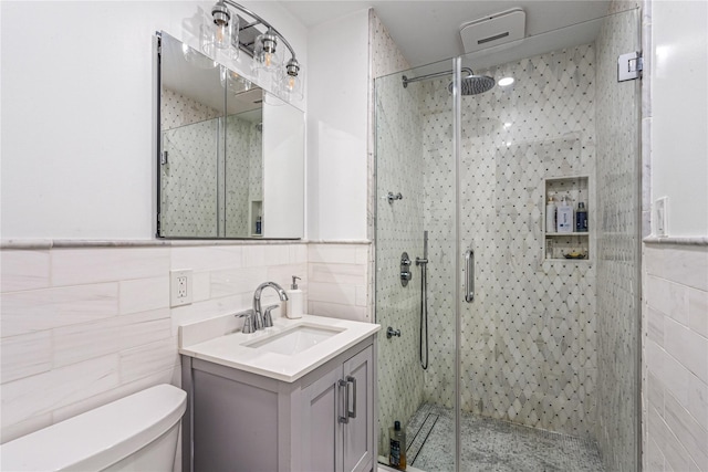 bathroom with tile walls, an enclosed shower, toilet, and vanity