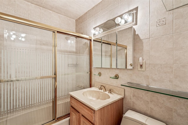 full bathroom featuring tile walls, shower / bath combination with glass door, vanity, and toilet