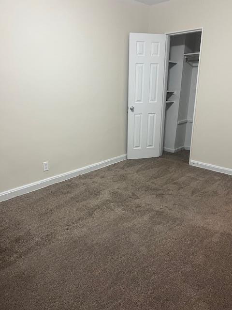 unfurnished bedroom featuring a closet and dark carpet