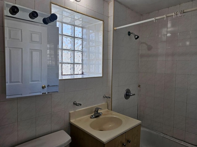 bathroom with vanity, toilet, and tile walls