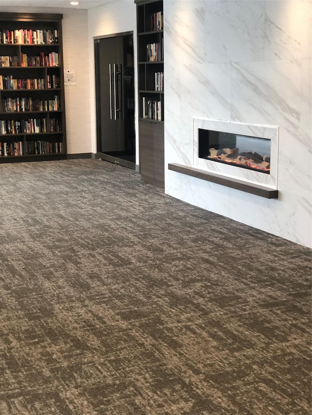 unfurnished living room featuring a fireplace, built in features, and tile walls