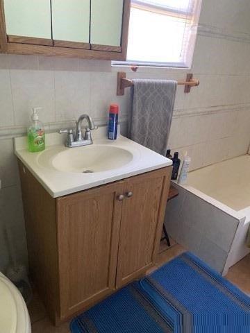 bathroom featuring decorative backsplash, a washtub, vanity, and toilet