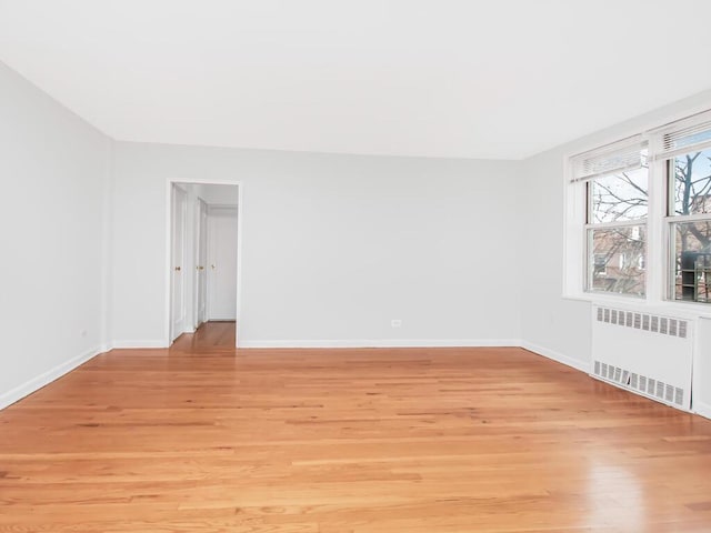 spare room featuring radiator and light wood-type flooring